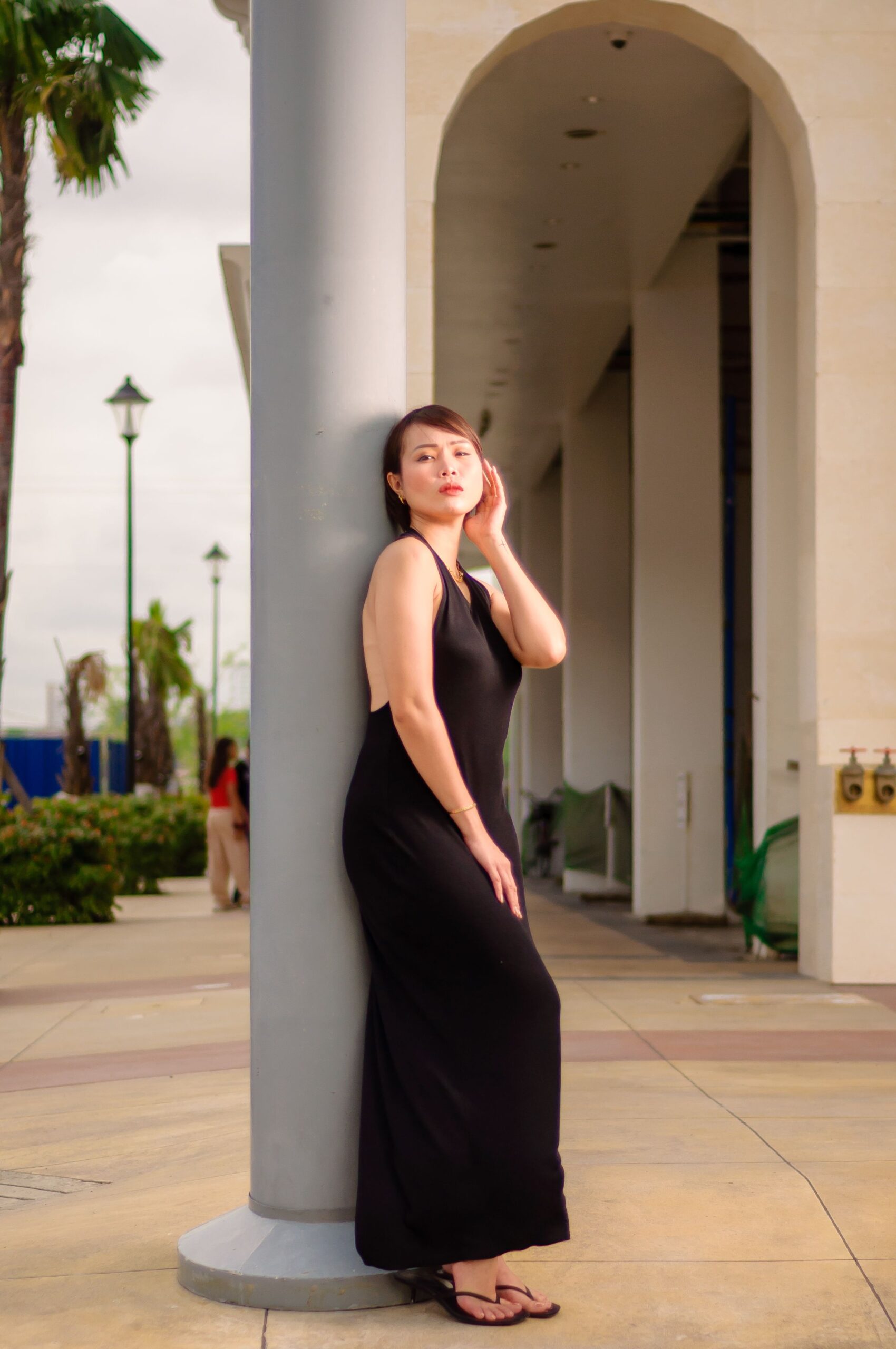 Woman wearing a black sleeveless maxi dress posing outdoors.