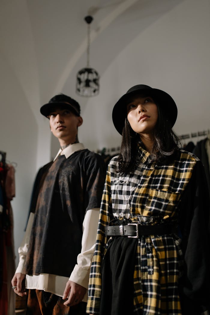 My Post A fashionable man and woman in stylish outfits posing indoors with hats.