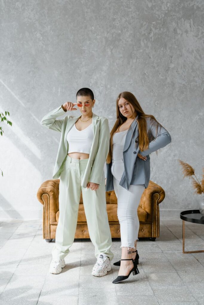 pexels photo 8433515 Two women in stylish outfits confidently posing in a modern indoor setting.