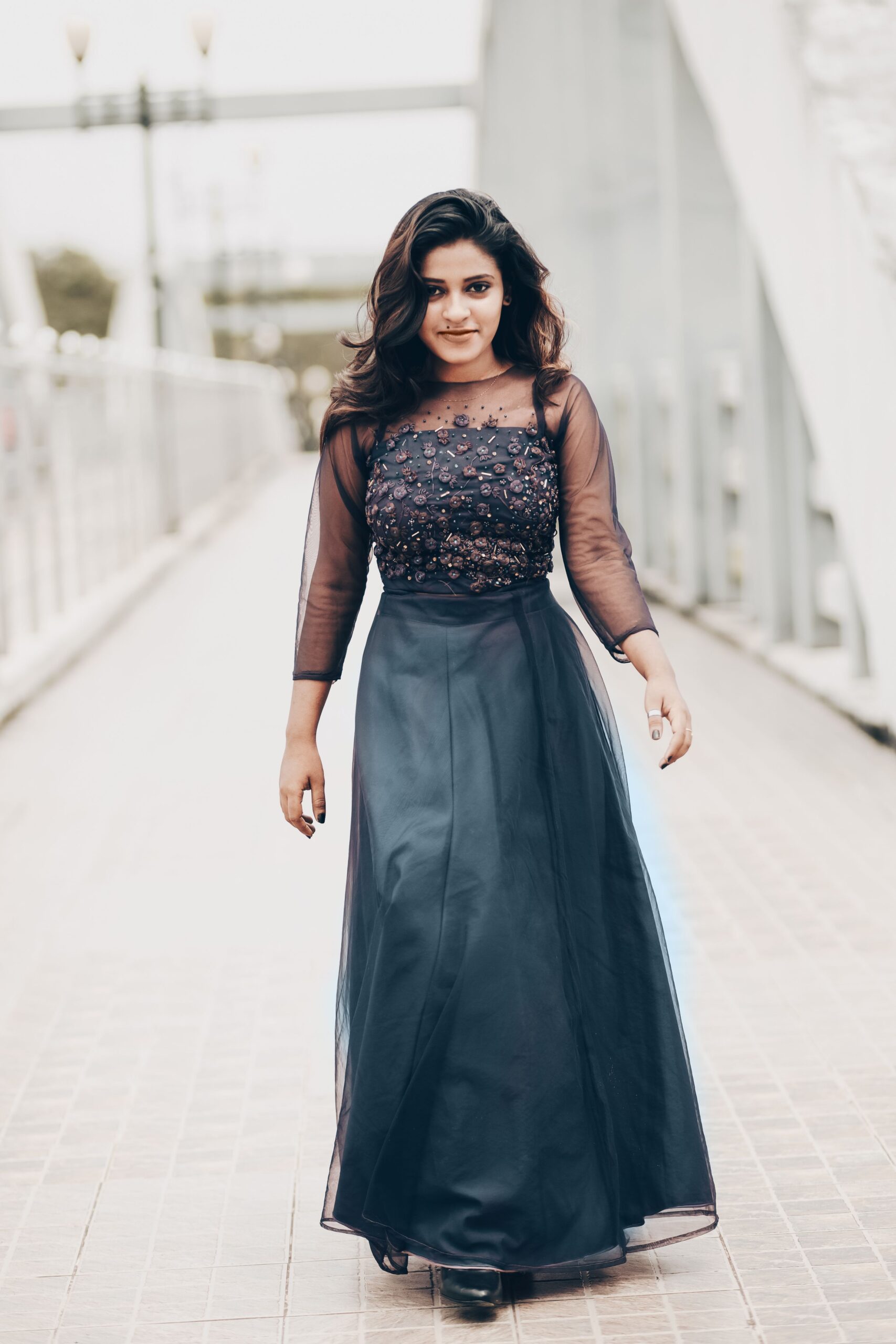 Woman wearing a black embellished long gown walking confidently.